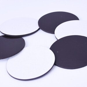 May include: A set of round, adhesive-backed magnetic discs in black and white. The discs are approximately 2 inches in diameter.