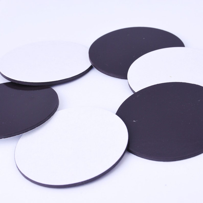 May include: A set of round, adhesive-backed magnetic discs in black and white. The discs are approximately 2 inches in diameter.