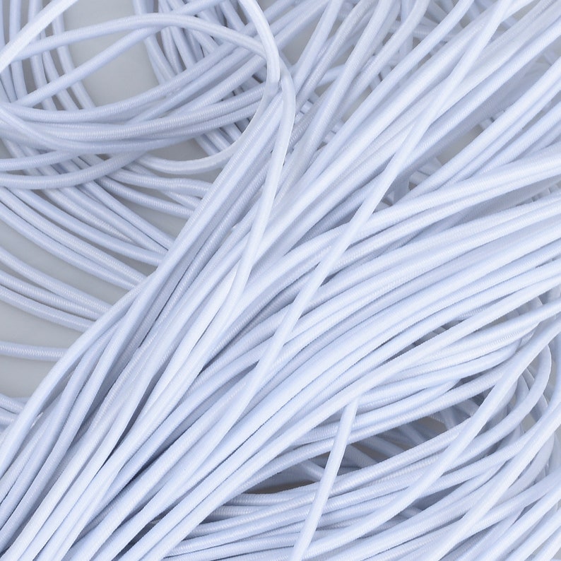 May include: A close-up of a large spool of white elastic cord. The cord is tightly wound and appears to be very stretchy.
