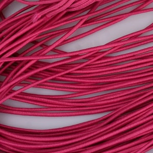 May include: A close-up of a bundle of bright pink elastic cord. The cord is soft and flexible, and it is ideal for crafting projects.