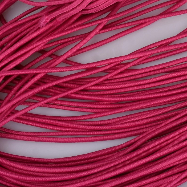 May include: A close-up of a bundle of bright pink elastic cord. The cord is soft and flexible, and it is ideal for crafting projects.