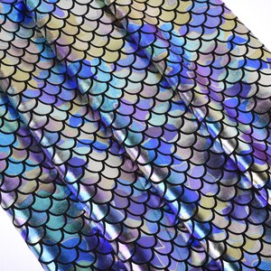 May include: Close-up of iridescent blue and purple fabric with a scale pattern. The fabric has a shiny, metallic finish.