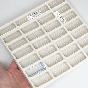 May include: White silicone mold with 25 rectangular cavities for making dominoes. The mold measures 230 mm by 225 mm. The cavities are 3/8 inch by 1 inch and 2 inch by 1 inch.