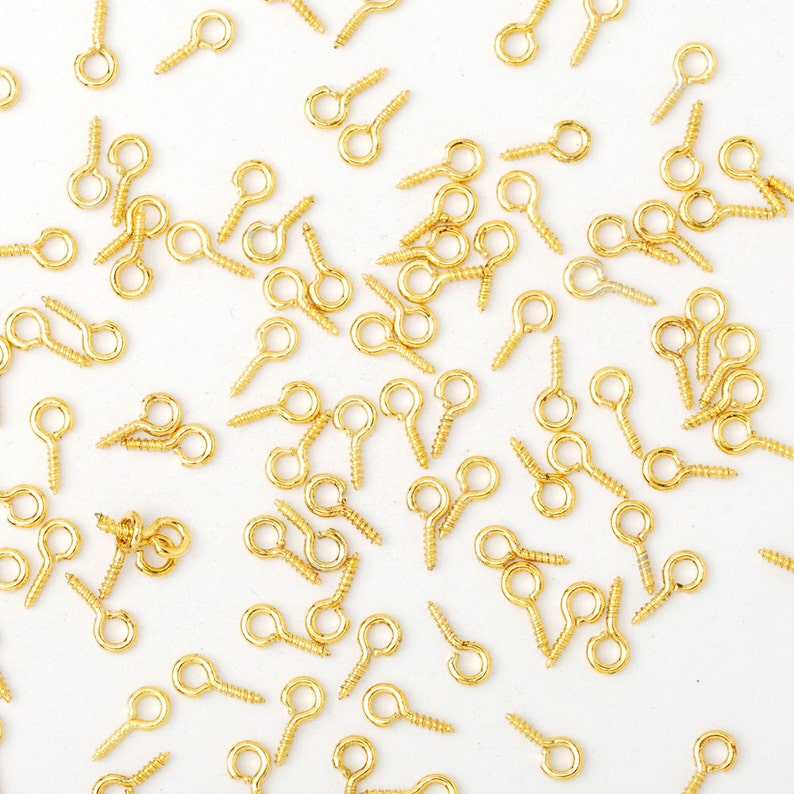 Peut inclure: Un grand nombre de crochets &agrave; &oelig;illets dor&eacute;s &agrave; visser. Les &oelig;illets sont petits et ronds, et les vis sont courtes et fines.