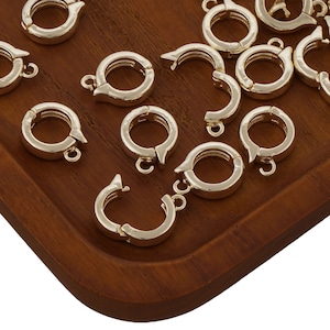 Peut inclure: Gros plan d'un groupe de fermoirs en métal doré, disposés sur une surface en bois. Les fermoirs sont conçus pour être utilisés pour la fabrication de bijoux ou d'autres projets d'artisanat.