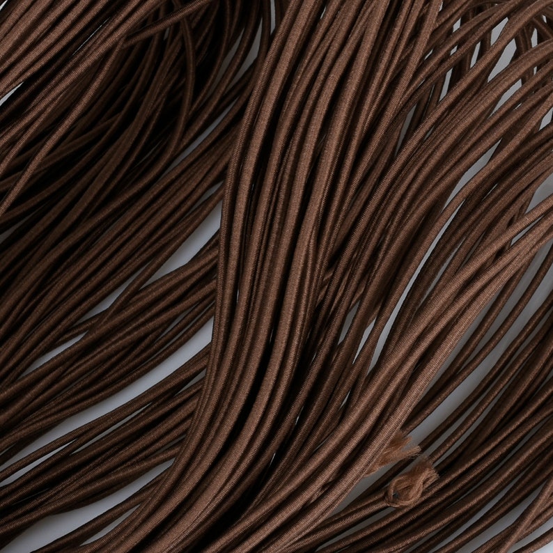 May include: A close-up of a bundle of brown elastic cord. The cord is smooth and has a slight sheen.