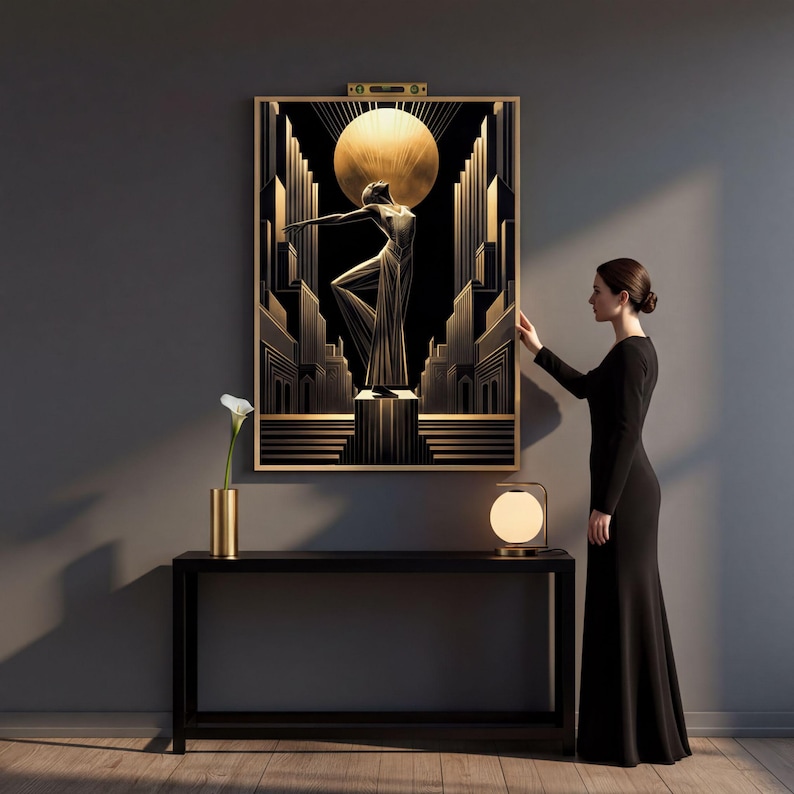 A woman in a black dress stands in front of a large framed artwork depicting a woman in a flowing dress, with a vase of flowers and a lamp on a table in front of her.