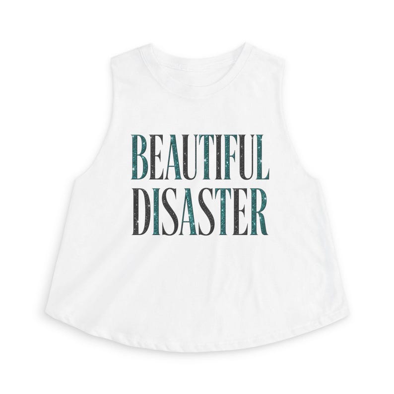 May include: White crop top with the text "BEAUTIFUL DISASTER" in a dark teal and black font. The text has a speckled design. The top has a rounded neckline and a sleeveless design.