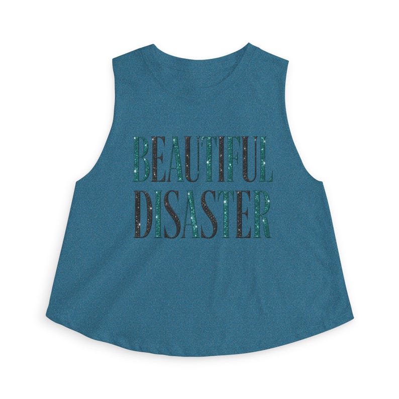 May include: Teal crop top with the words "BEAUTIFUL DISASTER" in a glittery font. The text is in a dark teal and black color, with white star-like accents. The top has a rounded neckline and sleeveless design.