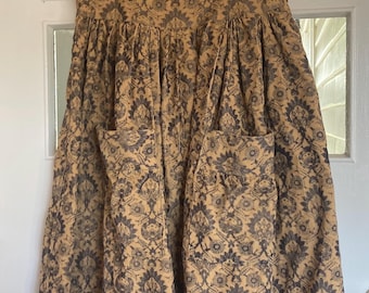 May include: A tan and navy floral print dress with a square neckline, short sleeves, and two front pockets. The dress has a fitted bodice and a flared skirt. The dress is hanging on a wooden hanger.
