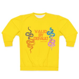 May include: A bright yellow crewneck sweatshirt featuring a graphic print of four snakes in orange, blue, and pink tones. The centre text reads "VALID BY DEFAULT" in orange block letters, with the smaller text "SINCE 2025" positioned directly below.