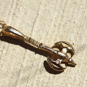 May include: A gold-toned necklace with a pendant shaped like a double-headed axe.