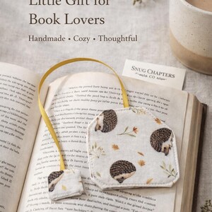 May include: A handmade bookmark with a yellow ribbon, featuring a repeating hedgehog pattern on a cream background. The bookmark is placed on an open book. The text "The Sweetest Little Gift for Book Lovers" is visible.