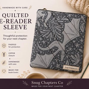 May include: A dark gray quilted e-reader sleeve featuring a repeating pattern of dragons, stars, and foliage. The sleeve has a zipper closure and a small fabric label that reads Snug Chapters Co. The text on the image reads Quilted E-Reader Sleeve.