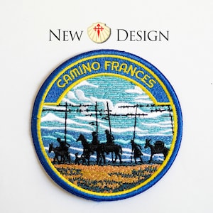 May include: Embroidered patch with a blue border and the words "CAMINO FRANCES" in yellow. The patch features a landscape with figures on horseback and donkeys, under a blue sky. The text "NEW DESIGN" is above the patch.