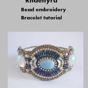 Könnte beinhalten: Ein Perlenarmband mit einem blauen Edelstein in der Mitte und schillernden weißen Perlen. Das Armband heißt "Rhaenyra" und ist ein Perlen-Stick-Armband-Tutorial.