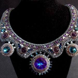 May include: A silver and purple beaded necklace with a large blue gemstone pendant and smaller blue gemstone accents.