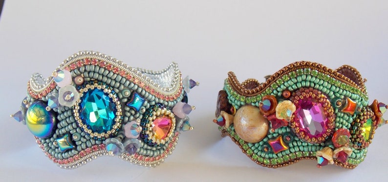 May include: Two beaded bracelets with a wavy design. One bracelet is silver with blue, green, and pink beads. The other bracelet is brown with green, pink, and gold beads.