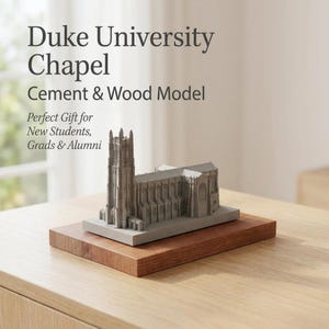 May include: A cement and wood model of Duke University Chapel. The gray chapel model sits on a rectangular, reddish-brown wooden base. The text "Duke University Chapel Cement & Wood Model" is displayed above the model.