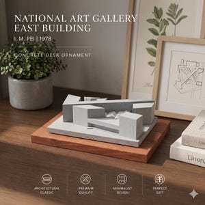 May include: A gray concrete desk ornament depicting the National Art Gallery East Building by I. M. Pei from 1978. The architectural model features geometric block forms on a rectangular base, presented as a solid, monochromatic structure.