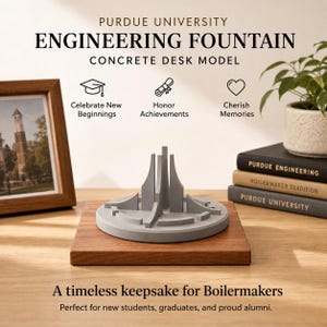 May include: A concrete desk model of the Purdue University Engineering Fountain, displayed on a wooden base. The text reads "Engineering Fountain Concrete Desk Model" and "A timeless keepsake for Boilermakers."