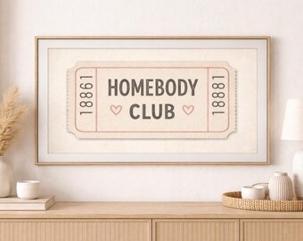 Könnte beinhalten: Gerahmter Druck mit einem Ticket-Design im Retro-Stil. Der Text lautet „HOMEBODY CLUB“ in einer Serifenschrift, mit den Zahlen 18861 und 18881 auf beiden Seiten. Zwei kleine rosa Herzen flankieren das Wort „CLUB“.
