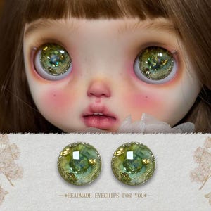 May include: Close-up of a doll's face with large, detailed green eyes. The eyes have a glittery, multi-toned appearance. Below the face are two matching eye chips with the text "--HEADMADE EYECHIPS FOR YOU--".