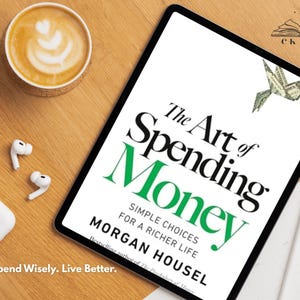 Peut inclure: Une tablette numérique affiche le livre "The Art of Spending Money" de Morgan Housel. Une tasse de café avec du latte art, des écouteurs blancs et un étui de chargement sont sur une surface en bois. Le texte "Spend Wisely. Live Better." est également visible.