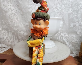 Vintage Elfenpuppe mit Herbstlaubmotiv, kitschige Herbstpuppenfigur, verspielte Erntedekoration, skurriles Thanksgiving-Geschenk