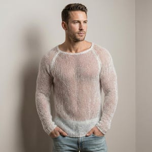 Könnte beinhalten: Ein langärmeliger, halbtransparenter Pullover in einem hellen Off-White- oder Cremeton. Das Kleidungsstück zeichnet sich durch eine lockere, grob gestrickte Struktur mit weitem Rundhalsausschnitt sowie gerippten Bündchen an Ärmeln und Saum aus.