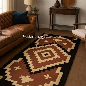 May include: A rectangular rug with a geometric pattern in black, tan, and rust-brown. The rug features a central diamond design and cross-like shapes. The text "Teppich Art Rugs" is visible on the rug.