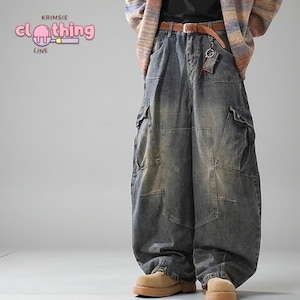 May include: Baggy, distressed denim cargo pants in a faded blue wash. The pants feature multiple pockets and a relaxed fit. The image also shows a brown belt and a keychain. The brand logo "KRIMSIE clothing LINE" is visible in the upper left corner.