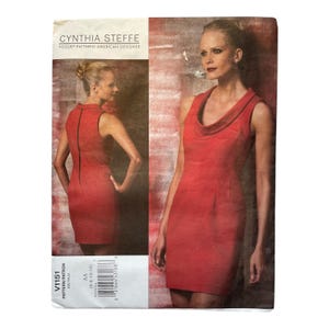 Puede incluir: Un patrón de vestido rojo sin mangas de Cynthia Steffe para Vogue Patterns. El patrón presenta un cuello de cisne y una silueta de funda. El tamaño del patrón es AA (6-8-10-12). La imagen incluye una foto de una mujer con el vestido.