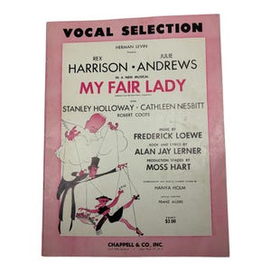 May include: A vintage "My Fair Lady" vocal selection sheet music book. The cover is pink with black and white illustrations of puppets and text. The book features the names Rex Harrison and Julie Andrews.