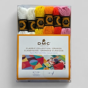 May include: A clear plastic box containing a collection of DMC tapestry wool skeins in various colors, including white, yellow, orange, and pink. The box features a label with the DMC logo and text in multiple languages, including "Classic Collection".