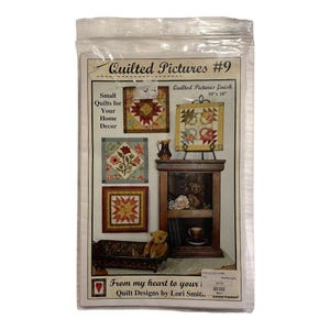 May include: A clear plastic package containing a pattern booklet titled Quilted Pictures #9 by Lori Smith. The cover displays four square quilt designs, a wooden shelf with a teddy bear, and a metal tray. The finished size is 10 inches by 10 inches.