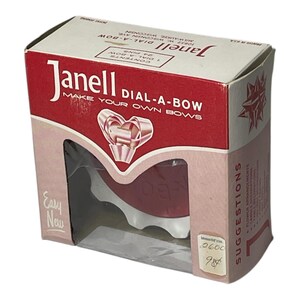 May include: A vintage Janell Dial-A-Bow box in red and white. The box has the text "Janell DIAL-A-BOW" and "MAKE YOUR OWN BOWS". The box contains a bow-making tool and is labelled "Easy New". The box is from Milwaukee, Wisconsin.