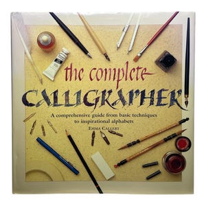 以下が含まれることがあります： 「the complete CALLIGRAPHER」というタイトルの正方形の本で、周りにカリグラフィーの道具が配置されています。本はベージュの背景で、タイトルは大きく濃い赤色のスクリプトで書かれています。さまざまなペン、インクボトル、白い絵の具のチューブが本の周りに散らばっています。