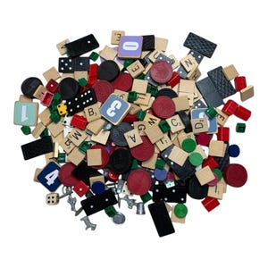 May include: A collection of game pieces including Scrabble tiles, dominoes, dice, and red, black, and green game tokens. The Scrabble tiles have letters and numbers. The dominoes are black with white dots. The dice are white with black dots.