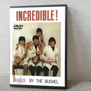 以下が含まれることがあります： 白い実験用ガウンと人形を着たビートルズの写真が写っているDVDケース。「INCREDIBLE！」の赤い文字と「THE BEATLES BY THE BUSHEL」の白い文字が書かれています。