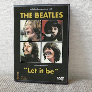 以下が含まれることがあります： ビートルズの「レット・イット・ビー」のDVDケース。カバーには、バンドメンバーの4つのポートレート写真と、黄色の映画タイトルがあります。DVDケースは黒で、「An intimate experience with The Beatles」というテキストが入っています。