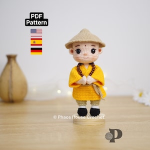 Pode incluir: Boneca de crochê de um monge com uma túnica amarela, chapéu marrom e sapatos pretos. A boneca tem uma expressão serena e um colar de contas. A imagem inclui o texto "PDF Pattern".