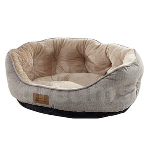 Op de afbeelding: Een grijs en beige huisdierenbed met een zacht, pluche interieur. Het bed heeft een afgeronde vorm met een laag profiel en een zwarte basis. Een klein bruin label met de tekst "pet dreams" is aan de zijkant genaaid.