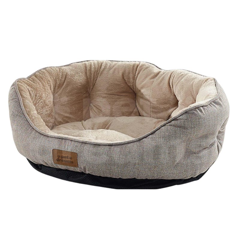 Op de afbeelding: Een grijs en beige huisdierenbed met een zacht, pluche interieur. Het bed heeft een afgeronde vorm met een laag profiel en een zwarte basis. Een klein bruin label met de tekst "pet dreams" is aan de zijkant genaaid.