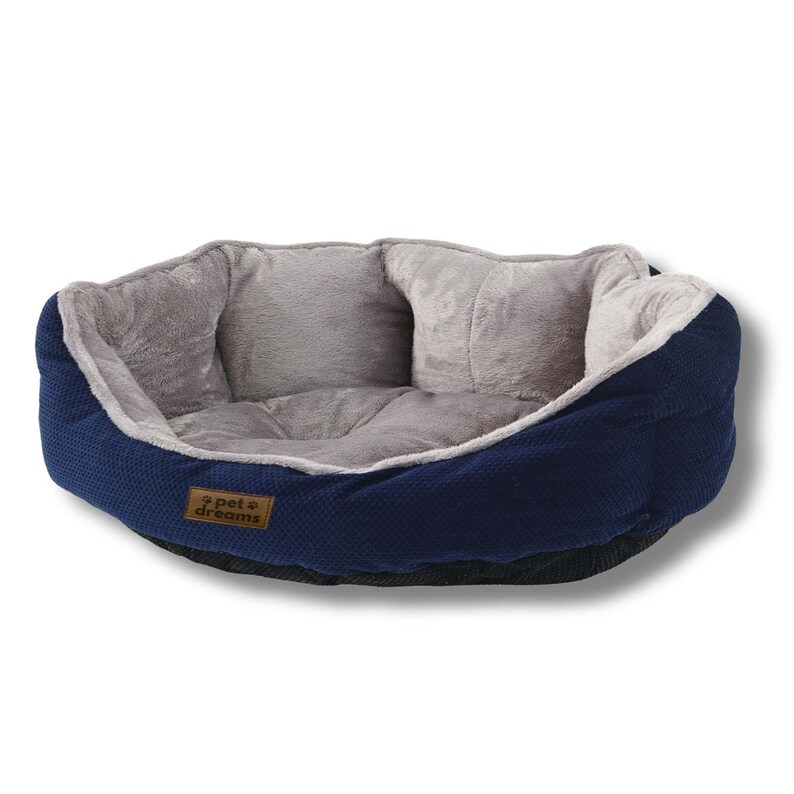 Op de afbeelding: Een marineblauw huisdierbed met een grijze pluche binnenkant. Het bed heeft een textuur aan de buitenkant en een zachte, gewatteerde binnenkant. De merknaam "pet + dreams" staat op een klein bruin label. Ontworpen voor het comfort van huisdieren.