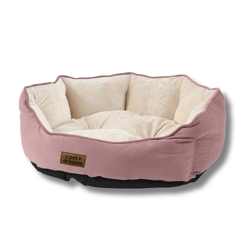 Op de afbeelding: Een roze dierenbed met een getextureerde buitenkant en een zacht, cr&egrave;mekleurig interieur. Het bed heeft een laag profiel met een zwarte basis en een bruin label met de tekst "pet dreams". Ontworpen voor kleine huisdieren.