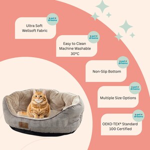 Op de afbeelding: Een grijs en beige huisdierenbed met een antislipbodem, gemaakt van "Ultra Soft Wellsoft Fabric". Het bed is machinewasbaar op 30&deg;C en OEKO-TEX&reg; Standard 100 gecertificeerd. Een oranje kat zit in het bed.