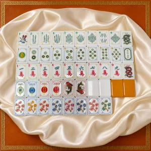 May include: A complete set of rectangular Mahjong tiles arranged in a grid. The tiles feature various colorful illustrations including bamboo sticks, circular coins, Chinese characters, dragons, flowers, and cardinal directions in English and Chinese text.