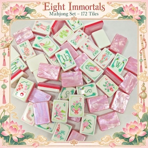 May include: A Mahjong set featuring 172 tiles with a mix of white tiles and pearlescent pink tiles. The white tiles display green and red illustrations of flowers, plants, and Joker characters. The text Eight Immortals Mahjong Set - 172 Tiles is visible.
