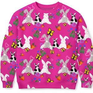 May include: A bright pink long-sleeve sweatshirt featuring an all-over repeating pattern of white, gray, and black rabbits, yellow butterflies, orange carrots, green leafy plants, and small pink and blue heart shapes across the entire garment.